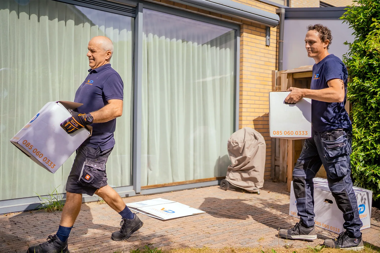 Twee verhuizers van Verhuisbedrijf Draagkracht dragen verhuisdozen naar binnen